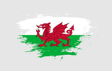 Grunge brush stroke with the national flag of Wales on a white isolated background