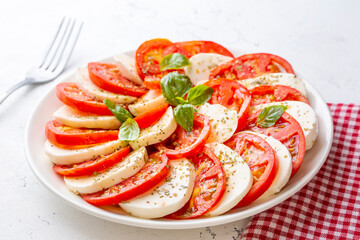 Italian caprese salad with sliced tomatoes, mozzarella, basil, olive oil