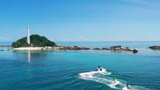 aerial zoom out of tourists on jet skis at lengkuas island in belitung indonesia on a sunny day