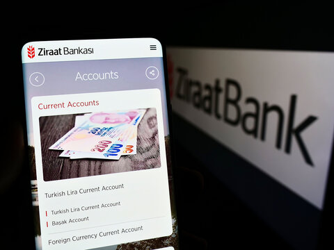 Stuttgart, Germany - 10-01-2022: Person holding cellphone with webpage of Turkish financial services company Ziraat Bank on screen in front of logo. Focus on center of phone display.