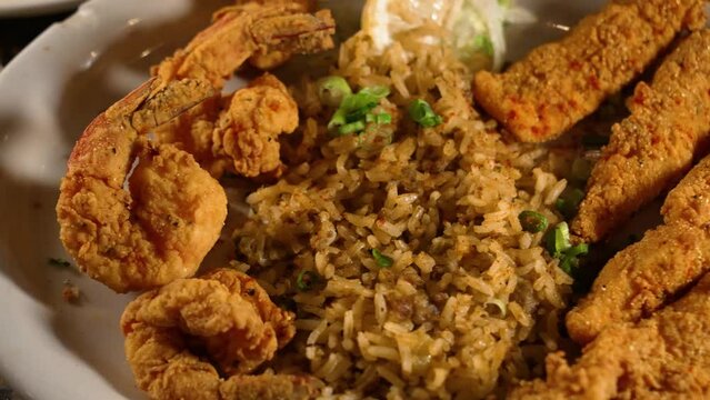 Dinner Plate Filled With Cajun Comfort Food Staples Dirty Rice Fried Shrimp Fish On Bottle Cap Tabletop, Slider Top Down Close Up 4K