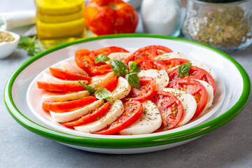 Italian caprese salad with sliced tomatoes, mozzarella, basil, olive oil