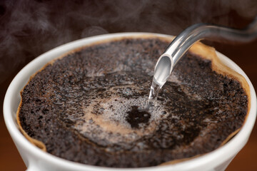 コーヒーの粉に熱いお湯を注いでドリップする
