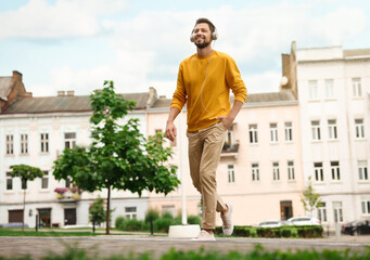 Handsome man with headphones walking on city street