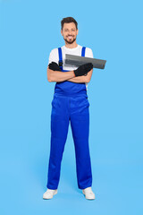 Obraz na płótnie Canvas Professional worker with putty knife on light blue background