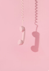Creative layout with pink retro phone handset on pastel pink background. 80s or 90s retro fashion...