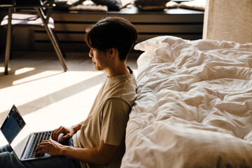 Asian young woman working with laptop while sitting on floor