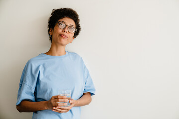 Young black woman smiling while posing with glass water at home