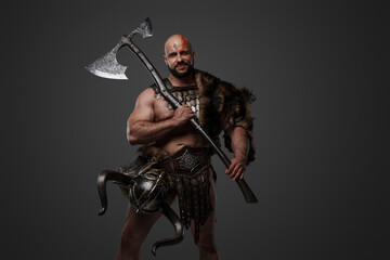 Naklejka premium Shot of scandinavian barbarian with fur and horned helmet holding two handed axe.