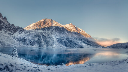 Bright sunrise in winter above lake Of Eye of the Sea, Poland. Light fog descends from Tatras...
