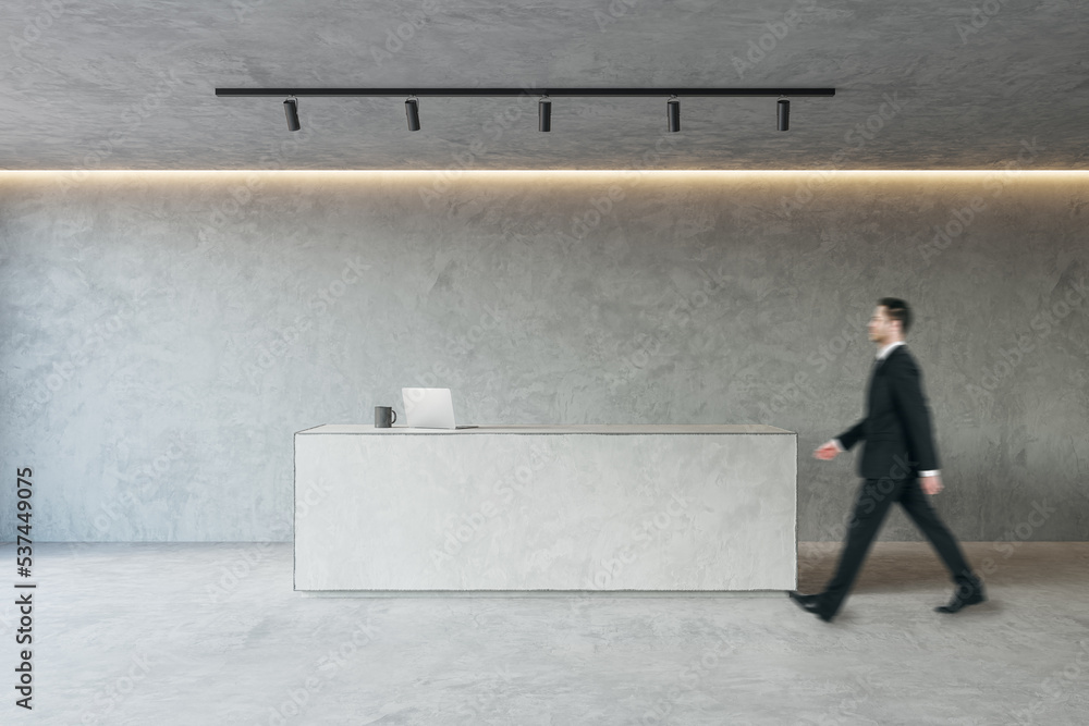 Wall mural side view of young businessman walking in modern concrete office reception interior with desk. lobby