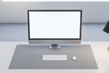 Close up of office table with empty white computer monitor and mock up place for your advertisement, lamp and keyboard on blurry background. 3D Rendering.