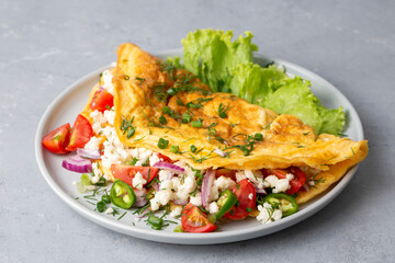 Homemade stuffed omelet on a plate. Egg omelet stuffed with fresh tomatoes, cheese and green parsley. Healthy vegetarian breakfast recipe.