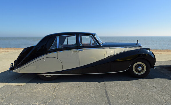 Beautiful  Vintage  Rolls Royce Motor Car Parked on seafront promenade beach and sea in background.