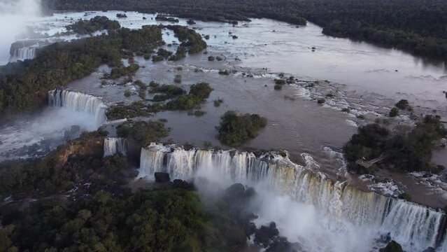 Stunning aerial shot of gigantic Iguazu Waterfalls between rocks during sunny day - Brazil and Argentina in South America - tourist spot with epic view from drone