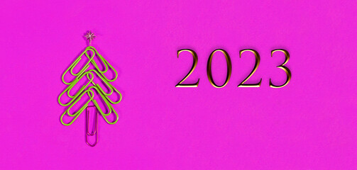 Concept 2023 merry xmas in the office. Xmas tree made of paper clips on the pink background. paper...