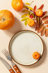 Autumn Halloween or Thanksgiving day table setting. Autumn background with an empty plate, cutlery, pumpkins. Thanksgiving background mock up. View from above.