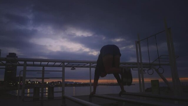 Young athlete doing Calisthenic and gymnastic exercises at the beach at sunrise