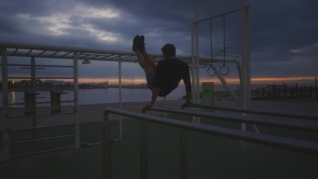 Young athlete doing Calisthenic and gymnastic exercises at the beach at sunrise