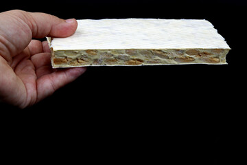 A hand holding a tablet of hard nougat, a typical dessert of Christmas in Spain, made with almonds