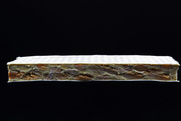 The whole nougat tablet is on a black background. Cross section of turron from Alicante, a typical...