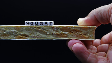 Fototapeta premium A hand holding a tablet of hard nougat, a typical dessert of Christmas in Spain, made with almonds