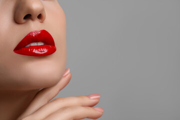Closeup view of woman with beautiful full lips on grey background. Space for text