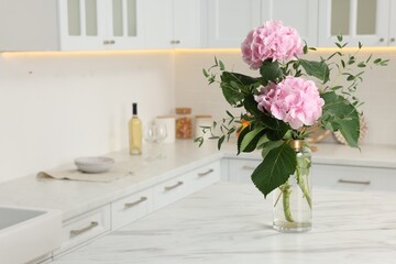 Beautiful pink hortensia flowers in vase on kitchen table. Space for text