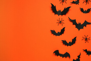 Flat lay composition with paper bats and spiders on orange background, space for text. Halloween celebration