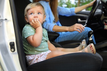 Mother with cigarette and child in car, focus on little girl. Don't smoke near kids