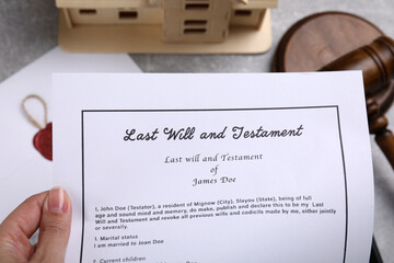 Woman holding last will and testament over table, top view