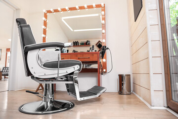 Stylish hairdresser's workplace with professional armchair in barbershop. Interior design