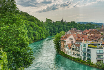 Fototapeta na wymiar River Aare, Bern, Switzerland with forest on a bank, typical Swiss houses on the other side. Lifestyle where people live in close contact with nature