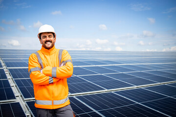 Portrait of smiling worker with arms crossed proudly standing on the rooftop after successful...