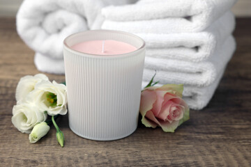 Obraz na płótnie Canvas Scented candle, folded towels and flowers on wooden table