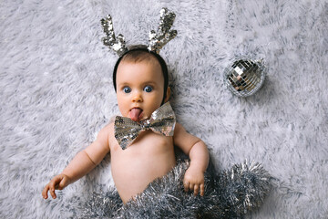 Baby with Christmas decoration lying on white background. New year and Christmas concept