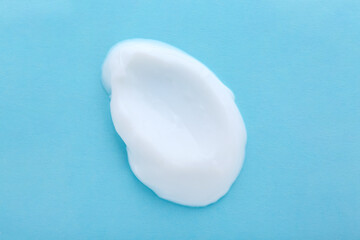 Sample of body cream on light blue background, top view