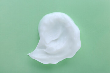 Sample of body cream on light green background, top view