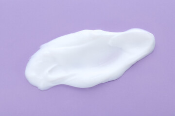 Sample of body cream on lilac background, closeup