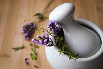 Mortar with fresh lavender flowers, green twigs and pestle on table, closeup. Space for text