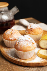 Tasty muffins served with banana slices on wooden table against dark background