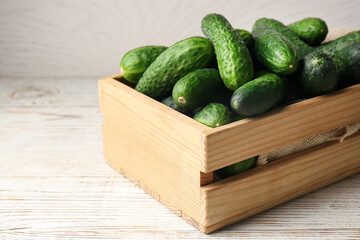 Crate full of fresh ripe cucumbers on white wooden table