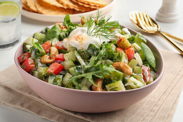 Bowl of delicious cucumber salad served on white table, closeup