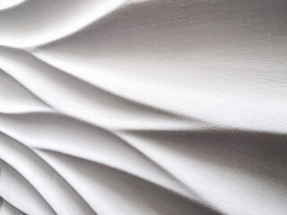 Abstract background formed by smooth wavy lines of gypsum on the wall. The difference of lights and shadows on a relief surface.