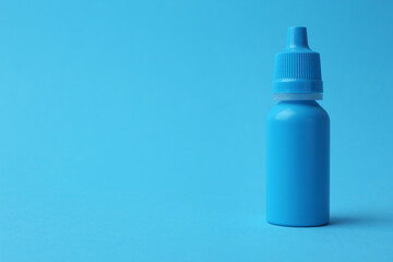 Bottle of medical drops on light blue background. Space for text