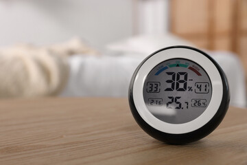 Digital hygrometer with thermometer on wooden table indoors. Space for text - obrazy, fototapety, plakaty