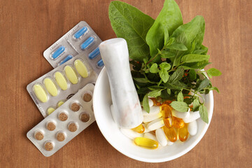 Mortar with fresh mint and pills on wooden table