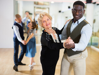 Elderly woman learning ballroom dancing in pair in dance studio