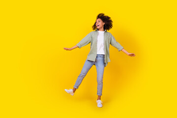 Fototapeta na wymiar Full length photo of nice young lady curly hair dance carefree look empty space wear trendy khaki look isolated on yellow color background