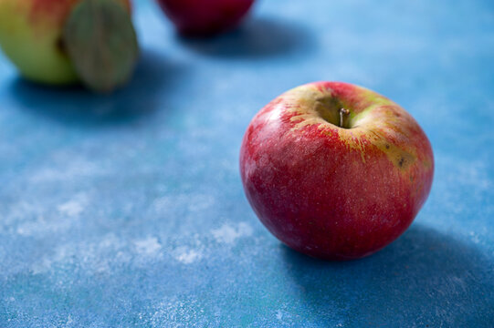 Fresh red apple freslhy picked, on blue background, lifestyle food photo, copy space